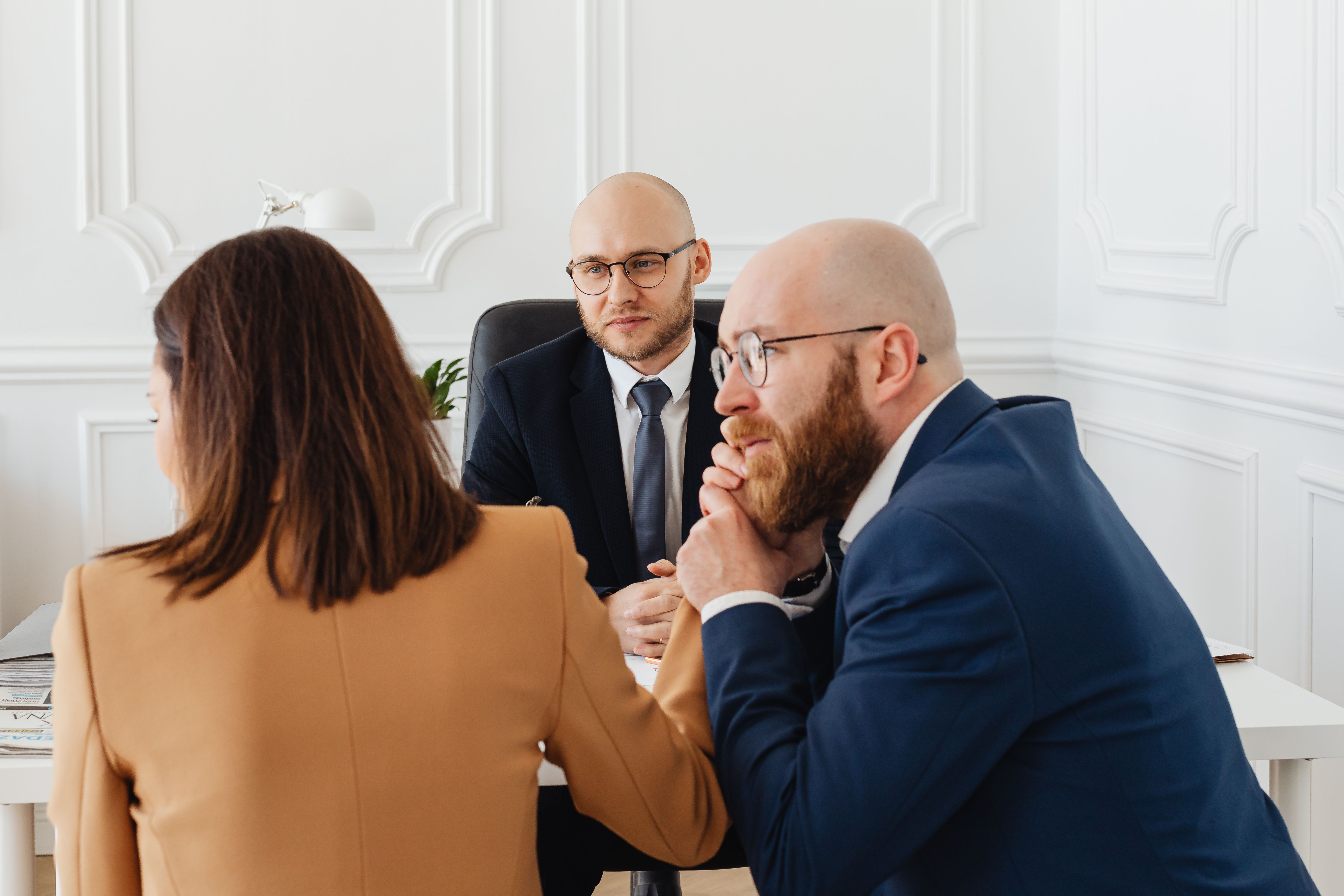 People in conversation across a desk in a bright modern office, the kind of moment where a well-timed review ask happens