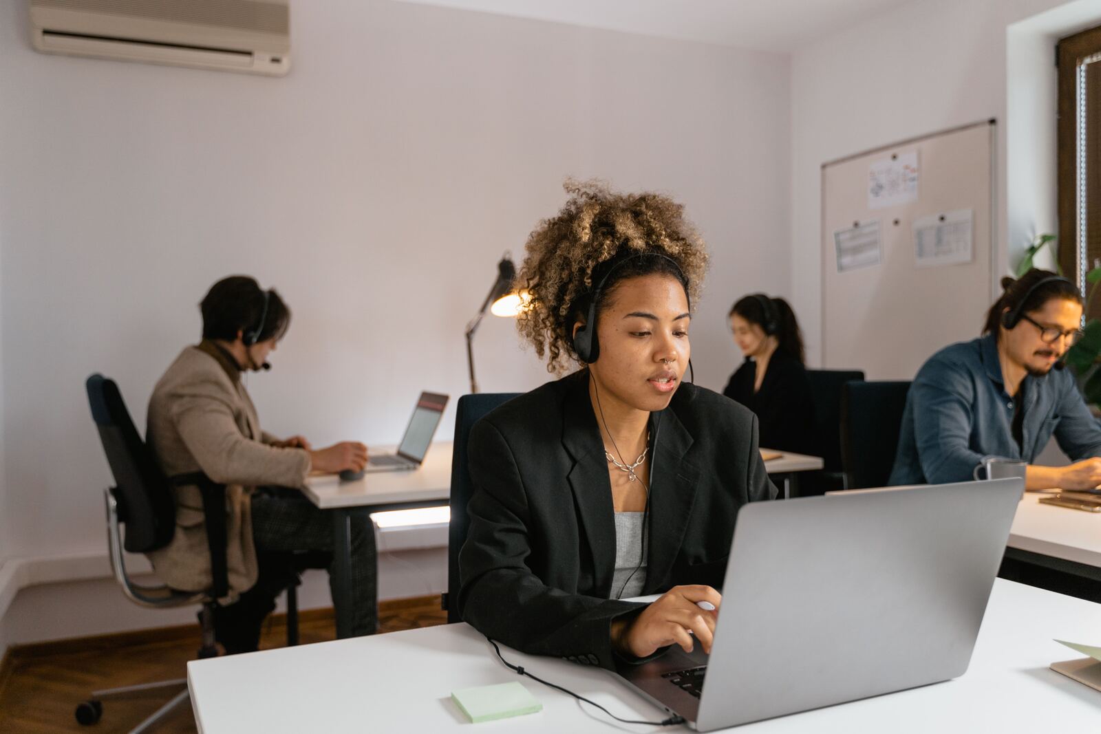 Law firm staff working at desks with telephone headsets in a shared office