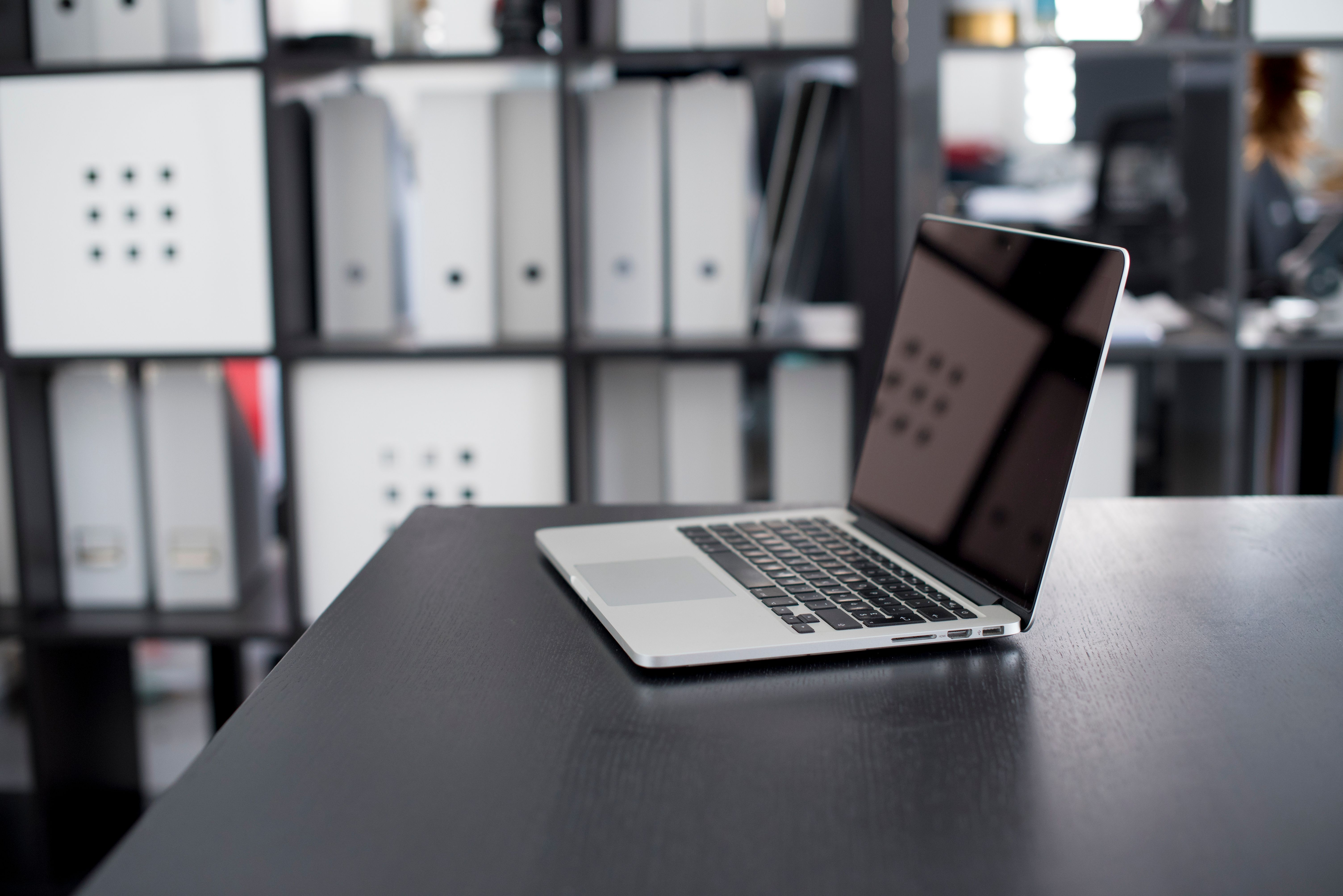 Desk with a plain closed laptop, an unbranded file organizer and a blank wall calendar beside a window