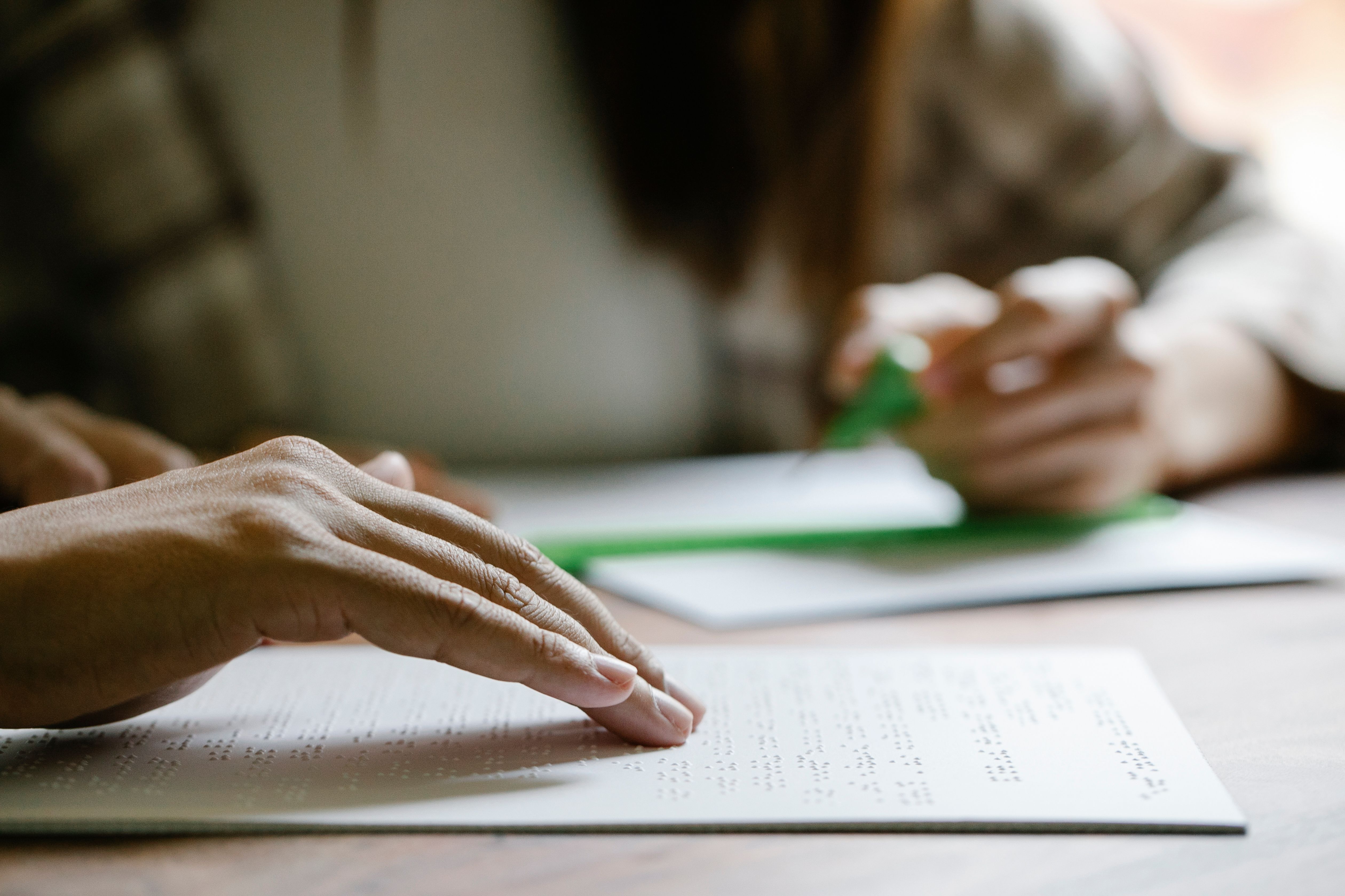 Close-up of hands reading a document printed in Braille at a desk