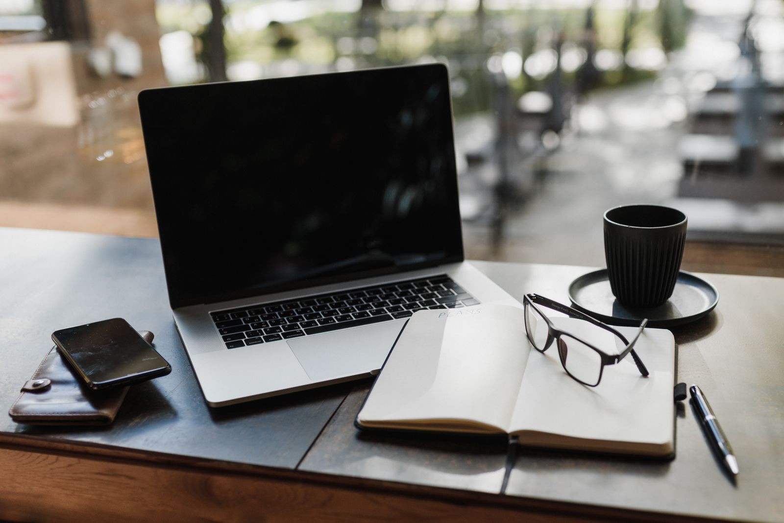 Laptop, notepad, glasses and coffee on a desk set up for planning