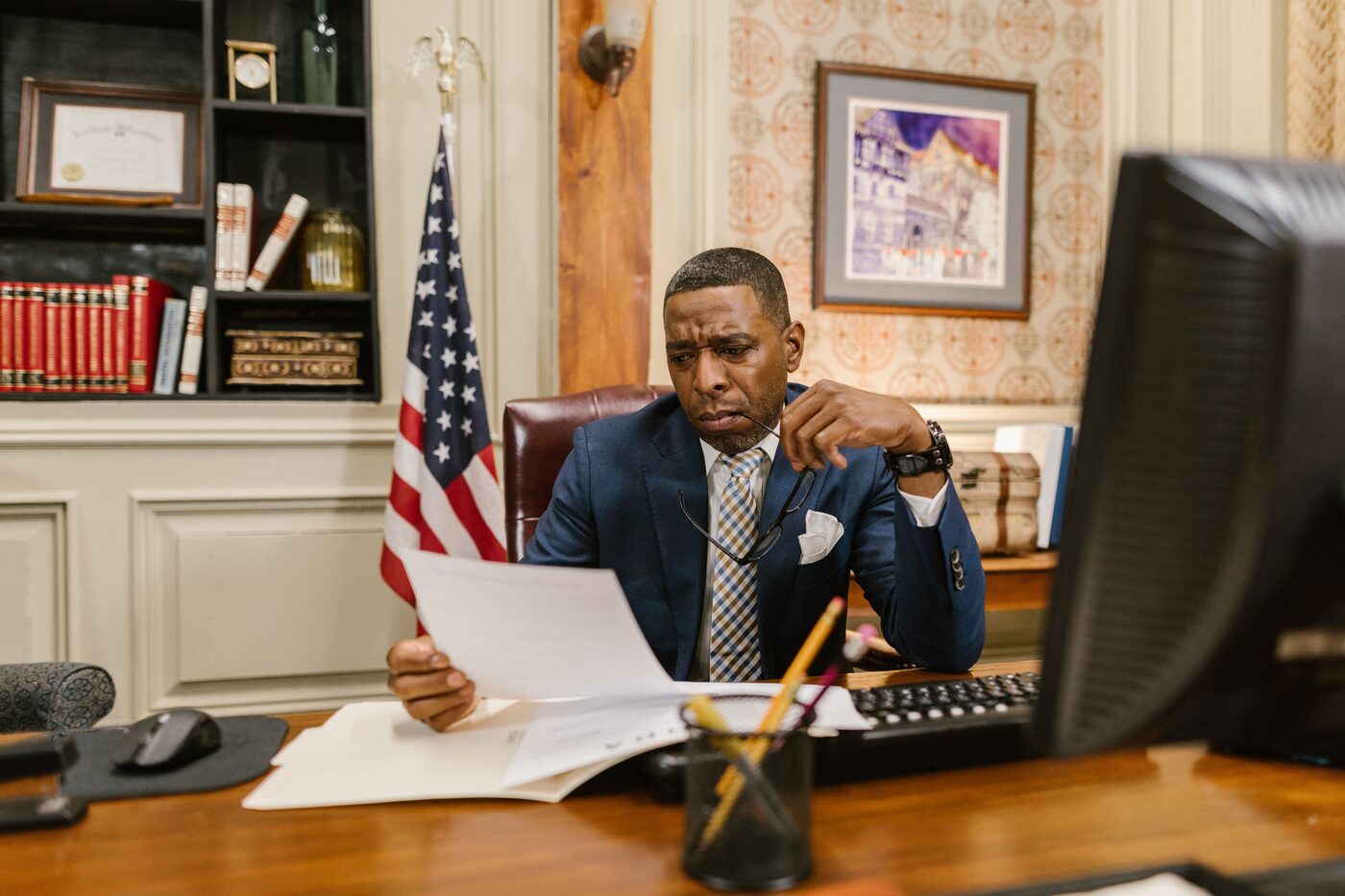 Professional at an executive desk pausing thoughtfully over paperwork